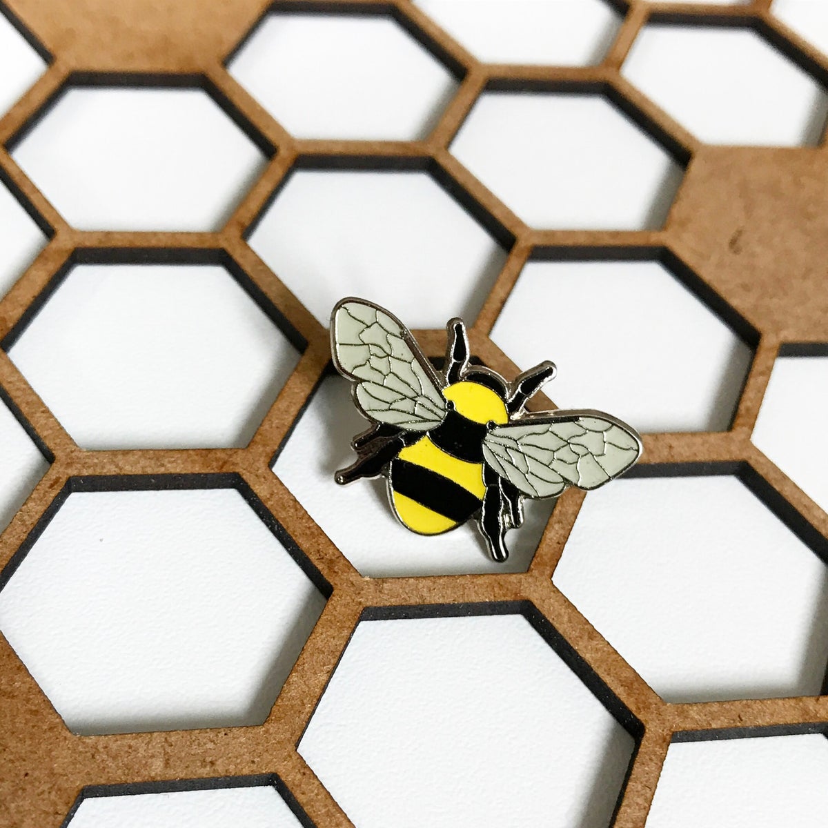 Manchester bee (yellow and black stripes, grey wings) enamel pin badge | Image courtesy of The Manchester Bee Company