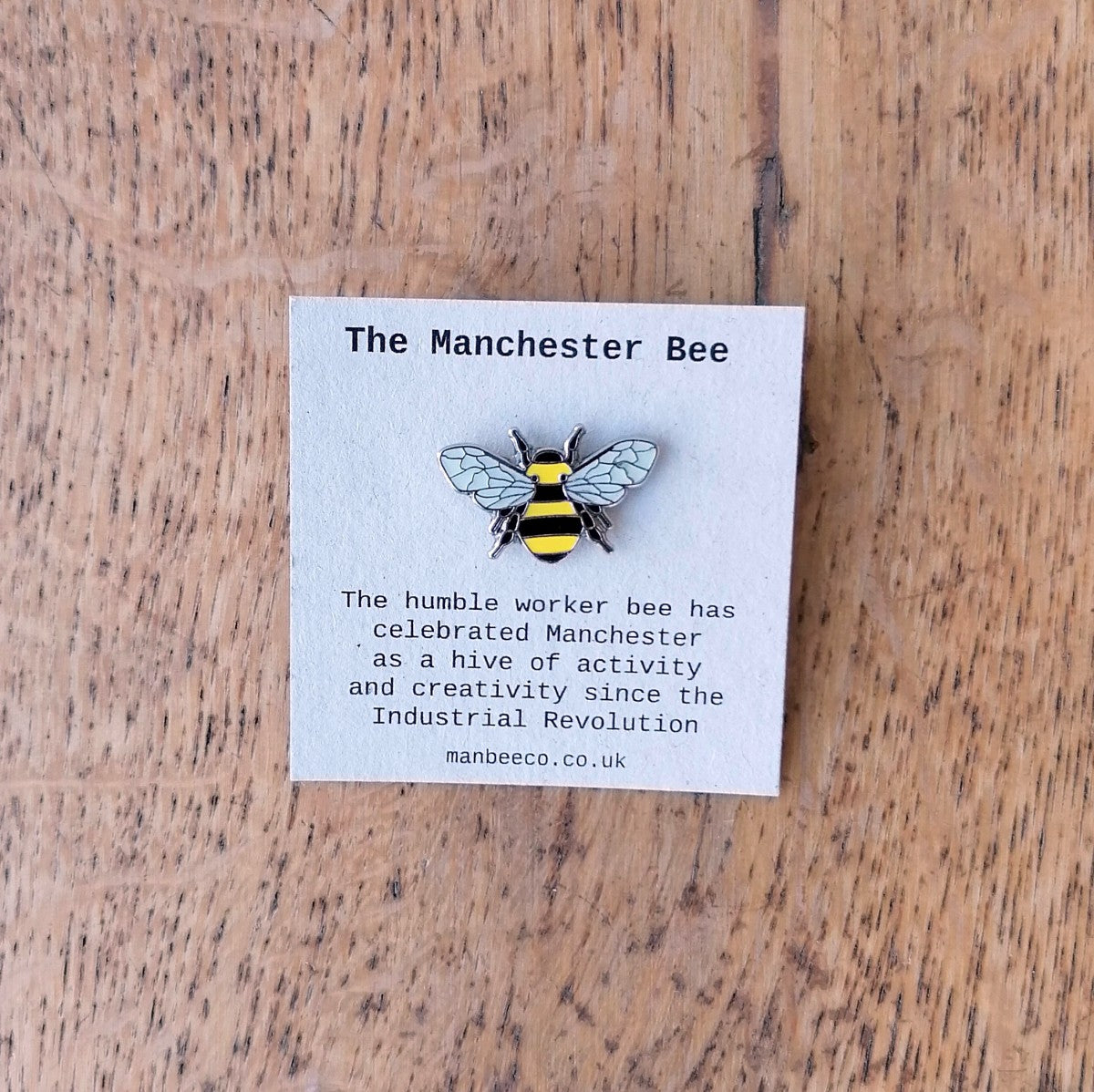 Manchester bee (yellow and black stripes, grey wings) enamel pin badge | Image courtesy of People's History Museum shop
